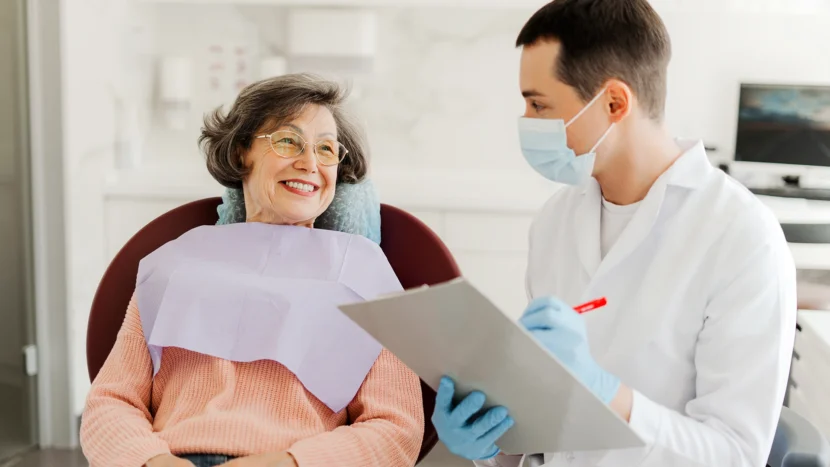 Imagen de una mujer en una revisión semestral sentada en un sillón dental mientras mira sonriente a su dentista