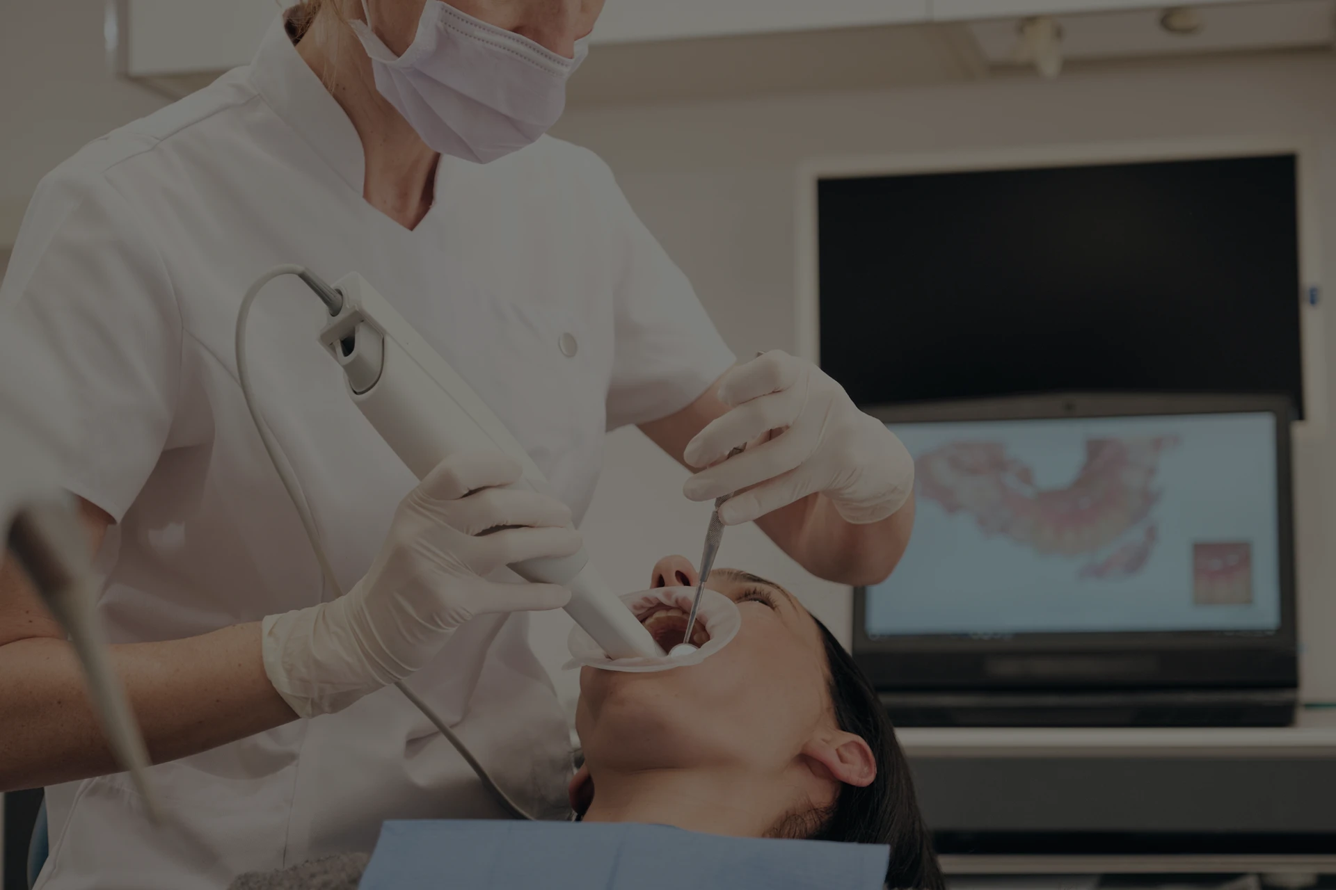 Imagen de una dentista introduciendo un dispositivo de profilaxis en la boca de un paciente mientras le realiza una limpieza bucal